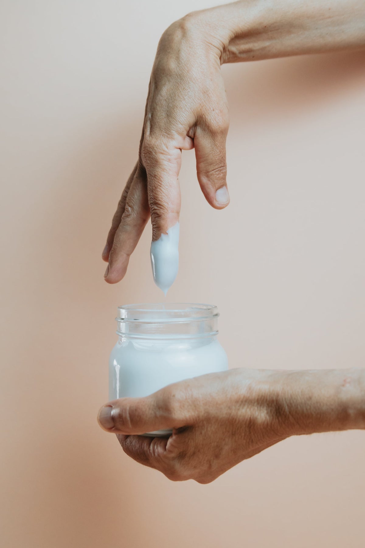 Mano con frasco de crema hidratante